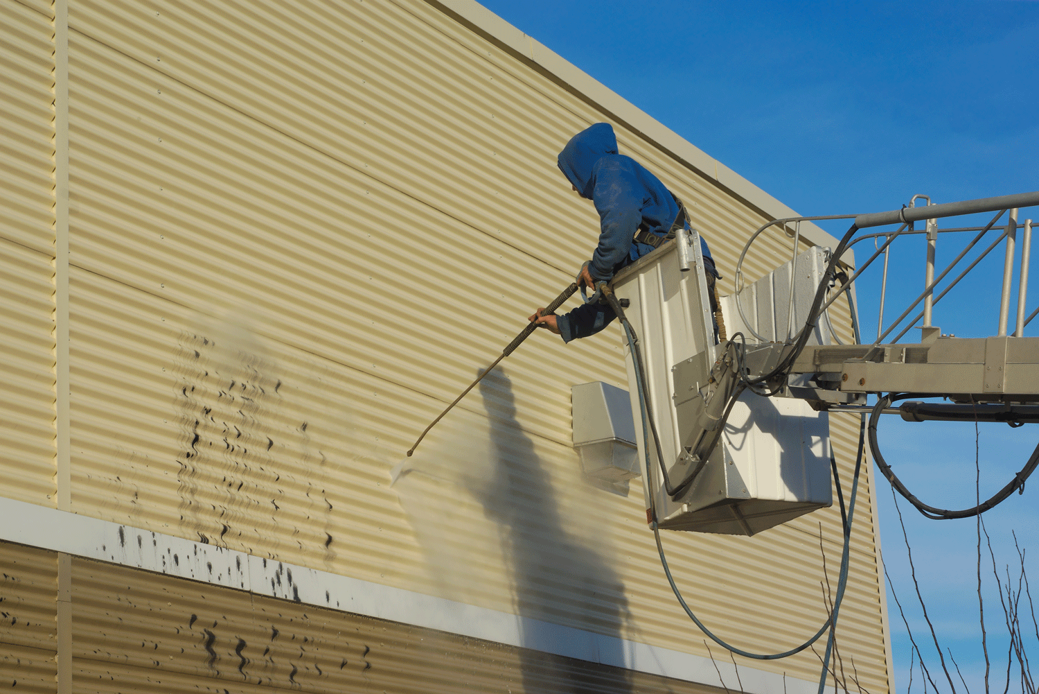 A technician cleaning the side of a building.